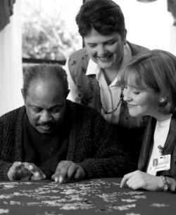 A student and instructor visit with a patient in a community nursing home.